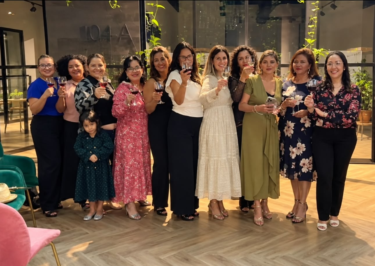 Grupo de mujeres sonriendo y brindando con copas de vino en un encuentro