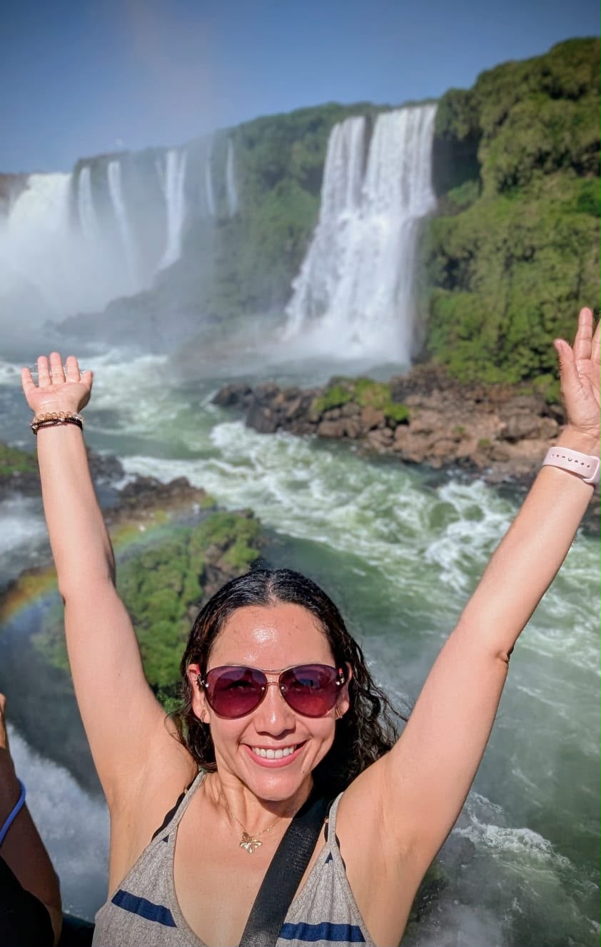 Viajera con los brazos en alto frente a las cataratas del Iguazú