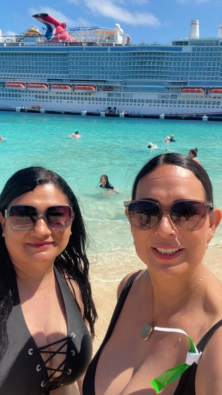 Verónica y Leticia en la playa de agua turquesa con un crucero al fondo